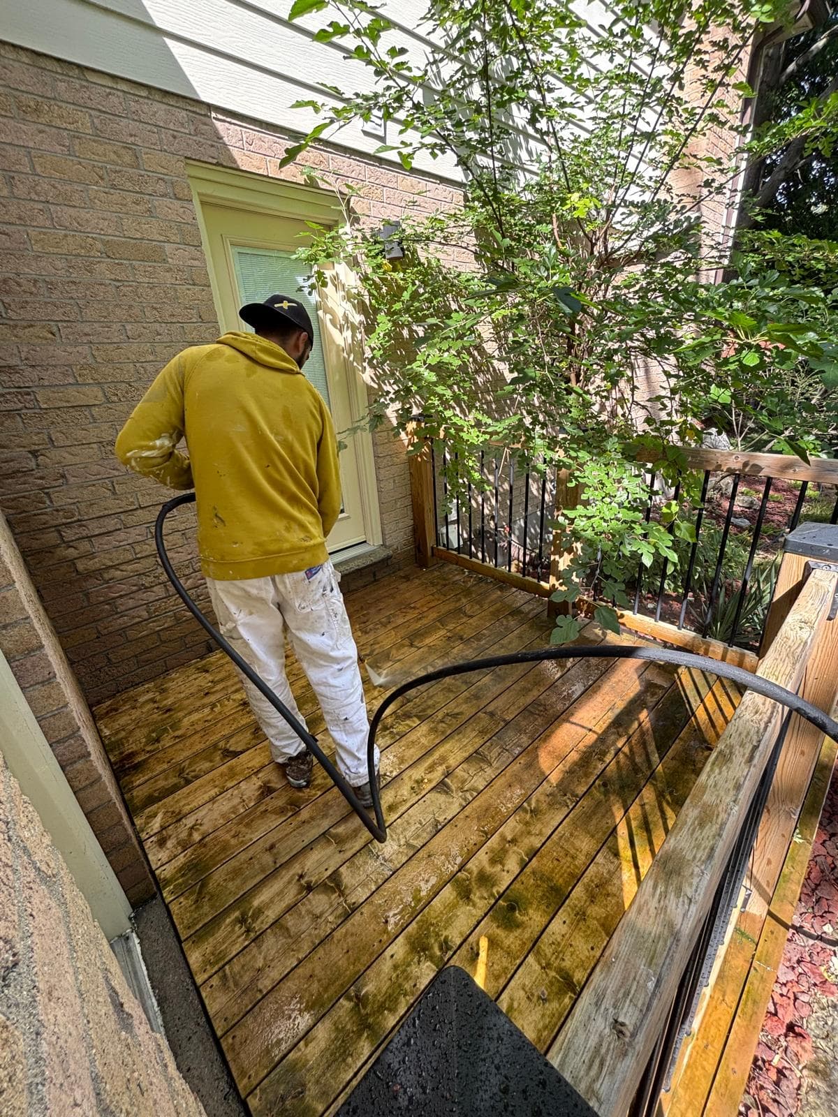 Painter pressure washing the side landing of a wood deck
