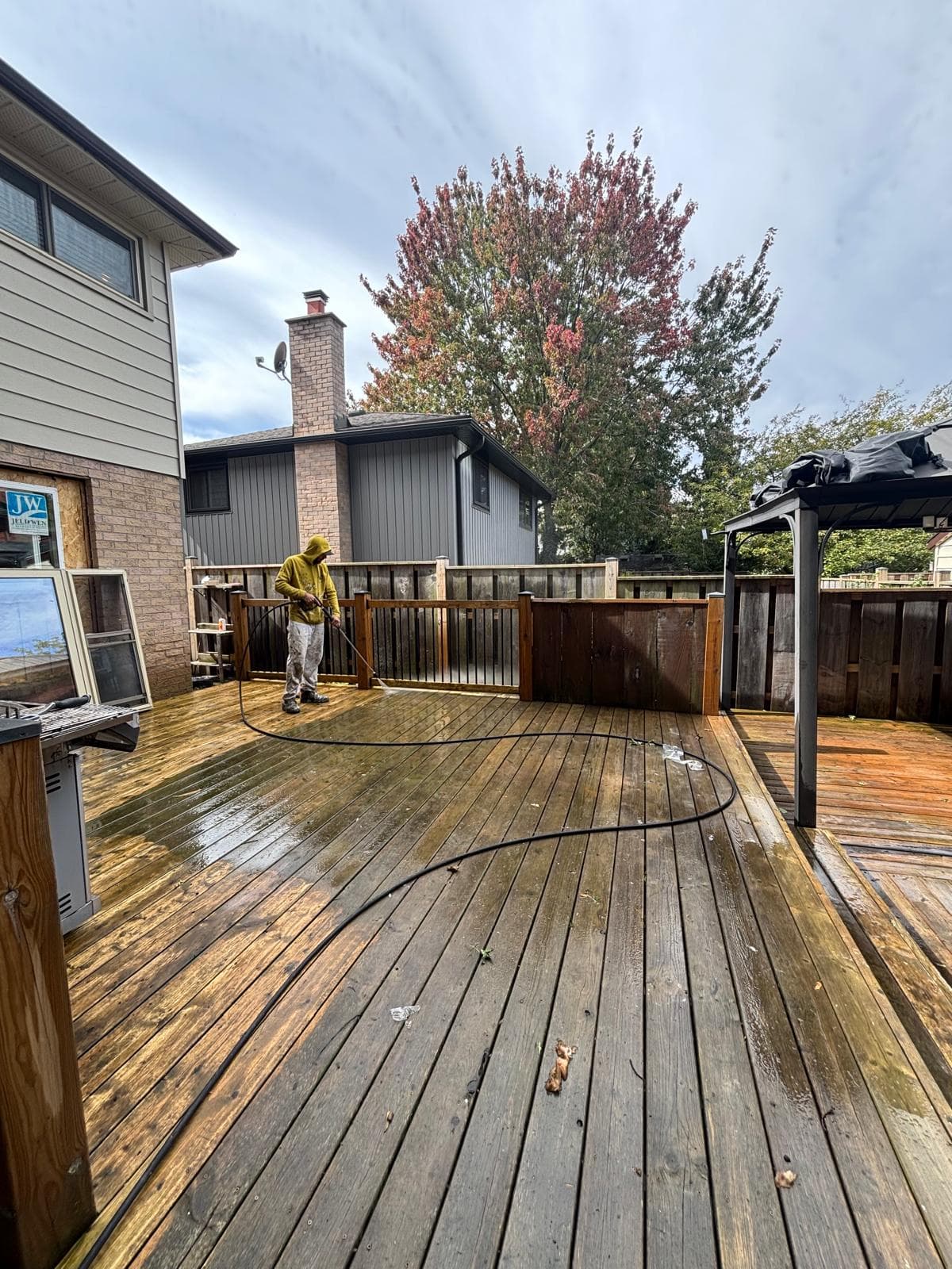 Wide view of a large backyard deck being pressure washed