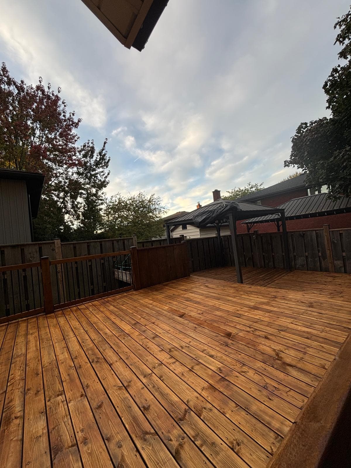 Completed warm brown stain finish across a large backyard deck