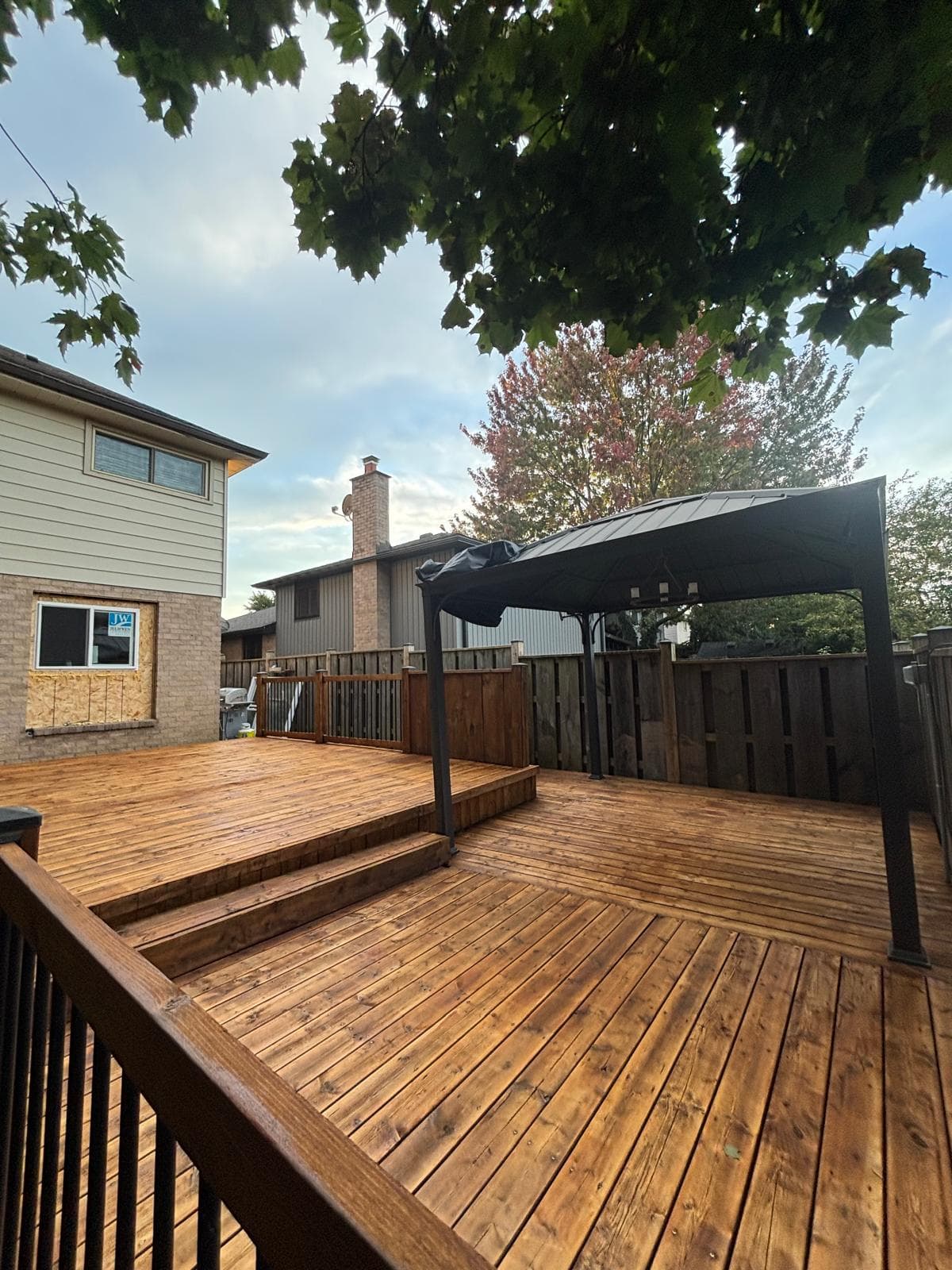 Wide view of a completed stained deck with gazebo and railings